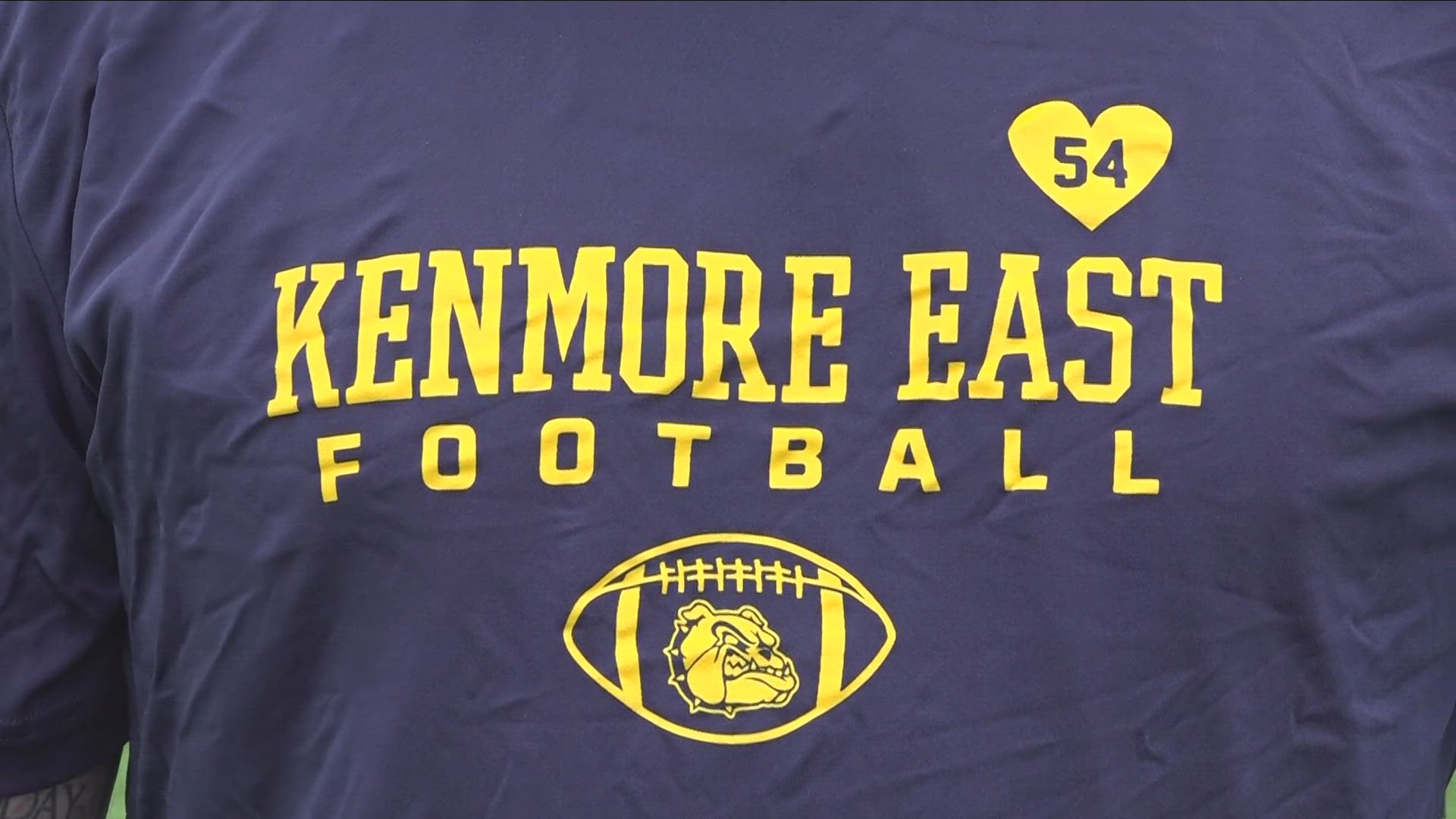 The t-shirt features the school's colors, blue and gold, as well as a heart with the number 54.